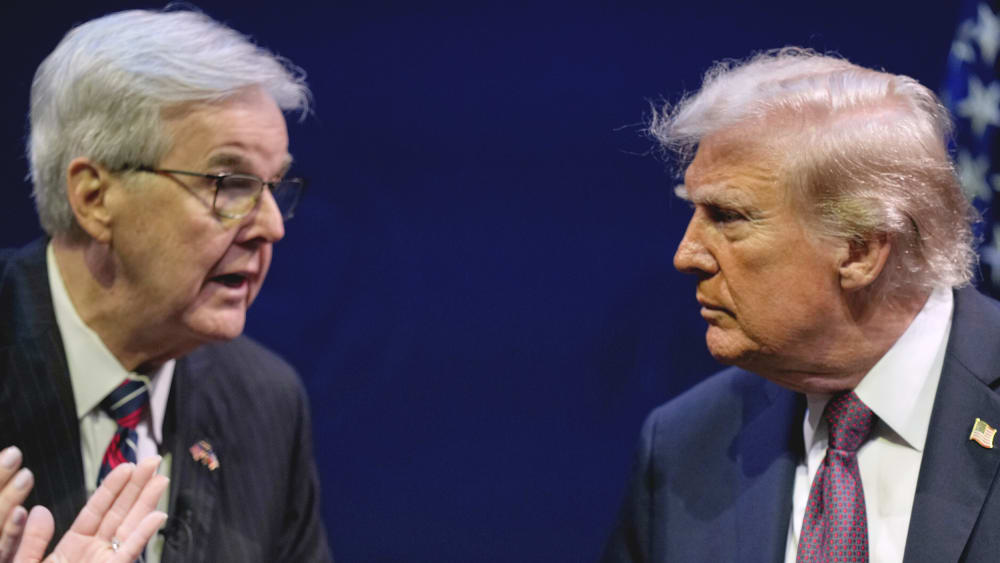 Dan Patrick, left, shaking hands with and talks to Donald Trump on stage.