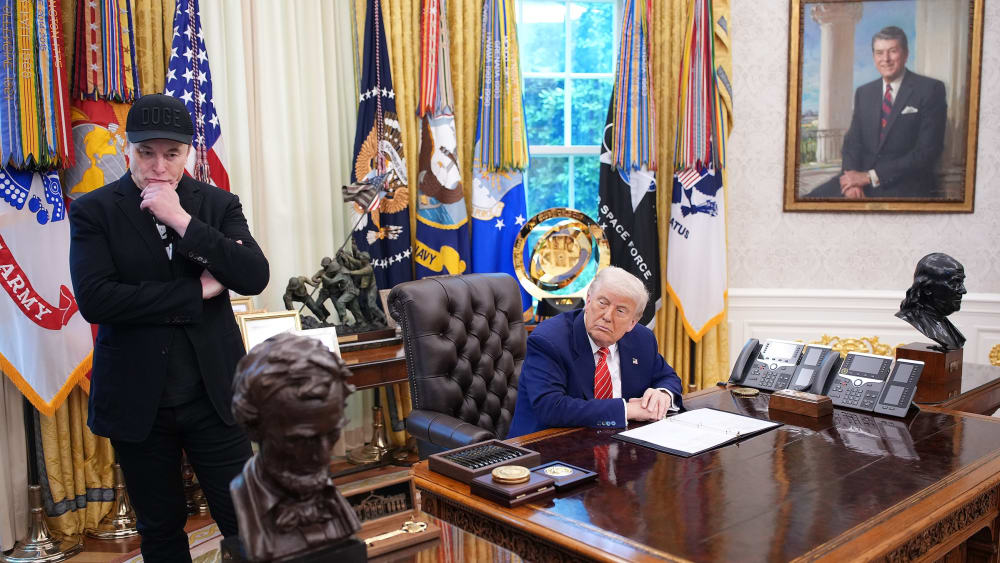 Tesla CEO Elon Musk and U.S. President Donald Trump listen to a question from reporters in the Oval Office.