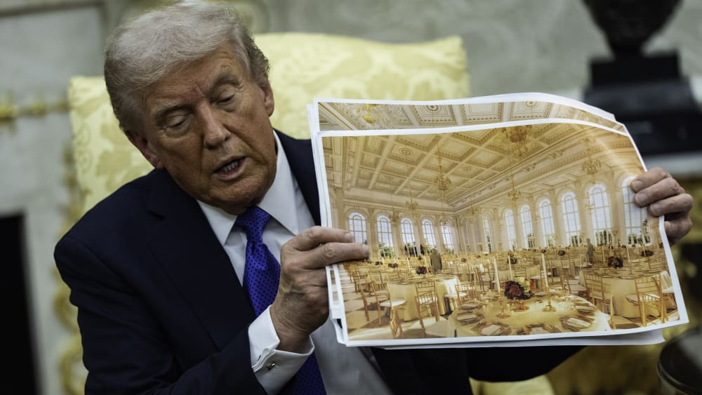President Donald Trump speaks holding a rendering of the new ballroom