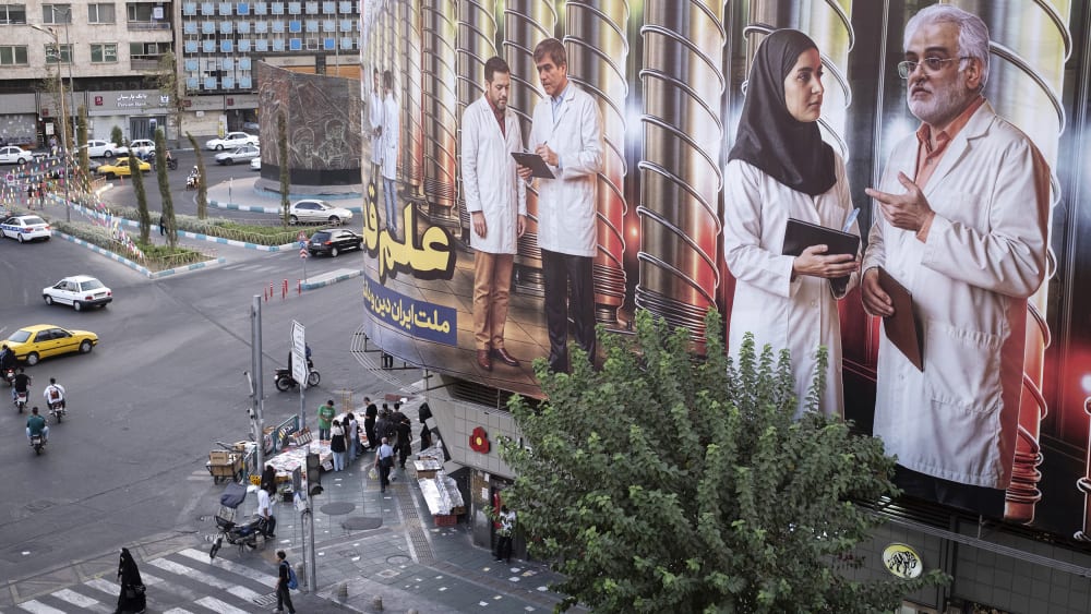 This photo shot from above shows a daily life scene where people walk on the street with a giant banner on the right side of the frame.