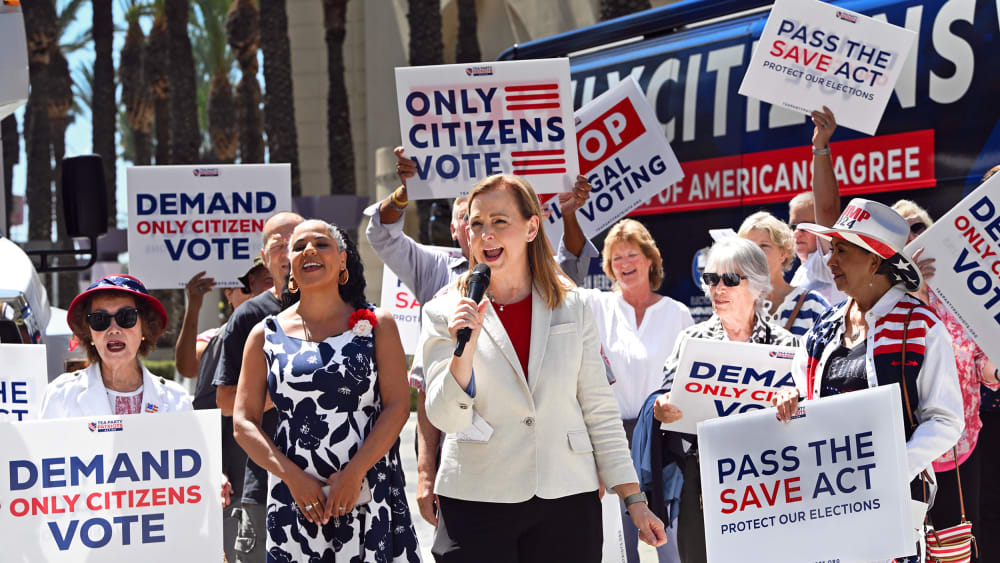 People hold signs saying "Only Citizens Vote" and "Pass the SAVE Act" outside.