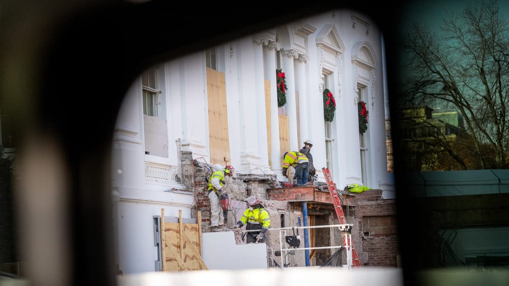Construction workers take down material where the East Wing used to connect to the White House.