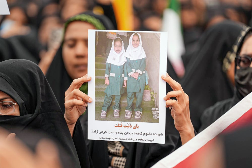 Mourners hold a portrait of a students during a funeral ceremony for children who were killed after a primary school was targeted in US and Israeli attacks in Minab, Iran.