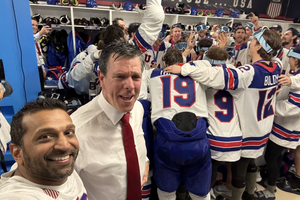 Kash Patel in a locker room with a group of men dressed for hockey are celebrating