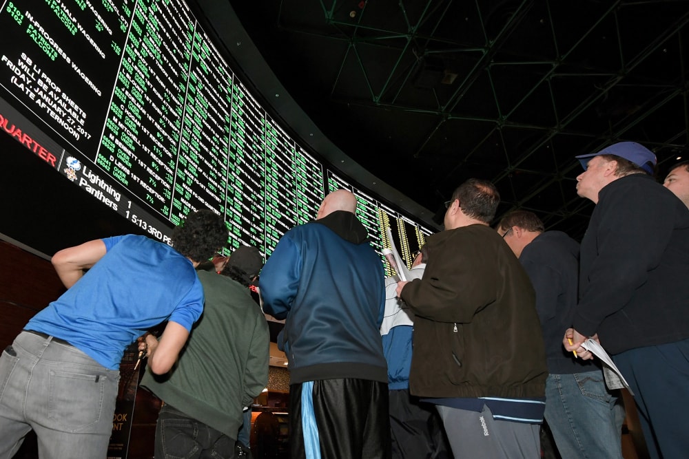 People look up toward a betting odds video board.