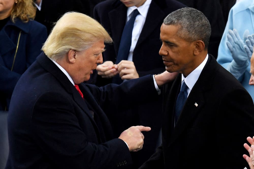 Donald Trump holds Barack Obama' shoulder while pointing at him with his other hand.