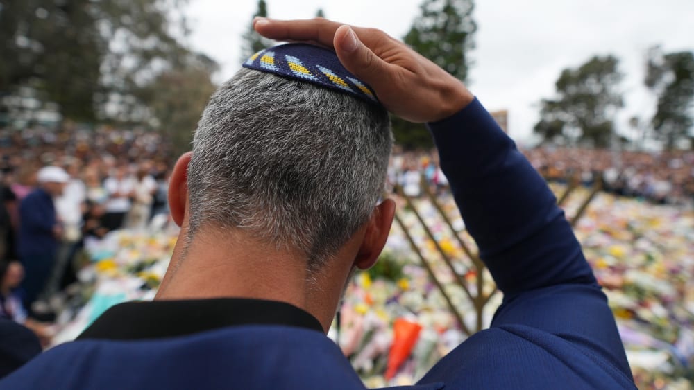 A man touches his kippah during a menorah lighting ceremony at a floral memorial for victims of the Bondi Beach shooting on Dec. 16, 2025 in Sydney, Australia.