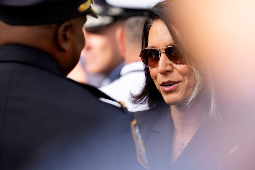 Tulsi Gabbard in sunglasses, speaking to an officer.