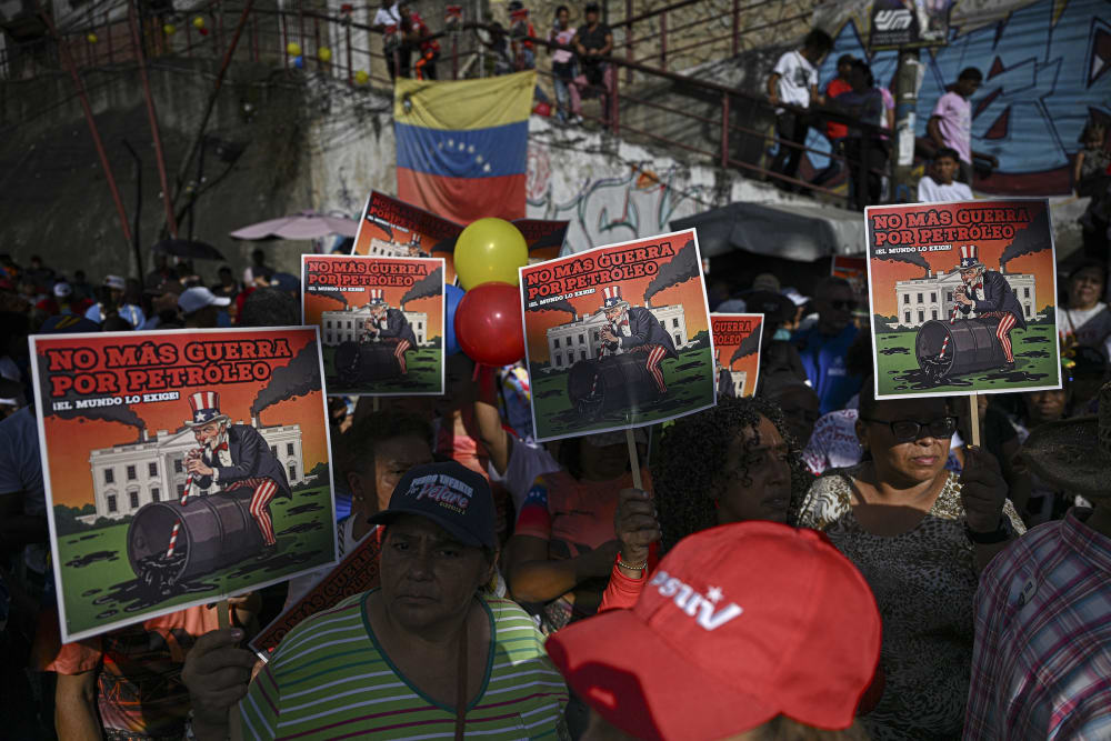 Supporters of Venezuelan President Nicolás Maduro show signs that read, in Spanish, “No more war for oil, the world demands it.”