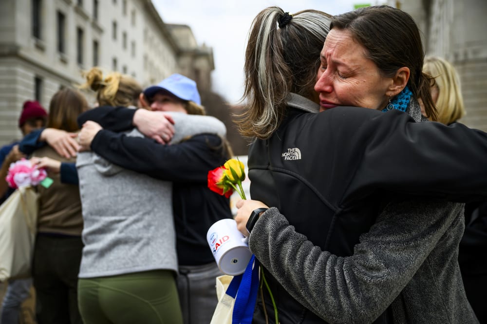 Prarie Summer, a USAID contractor for almost 10 years, right, cries as she embraces a Alexandra Jung after leaving the agency's former offices at the Ronald Reagan Building and International Trade Center.