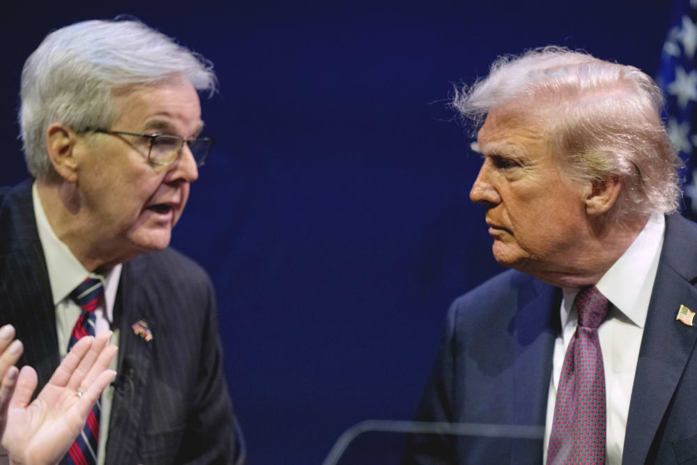 Dan Patrick, left, shaking hands with and talks to Donald Trump on stage.