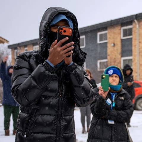 People use their phones to record and blow whistles in the snow.