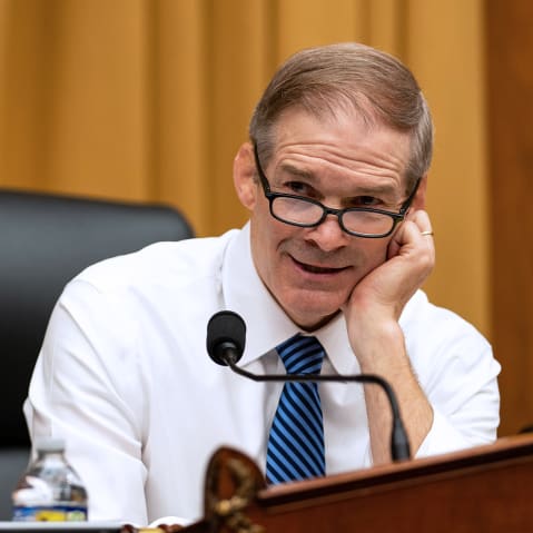 Jim Jordan, right, rests his head on his hand as he talks to a person turned away from the camera.