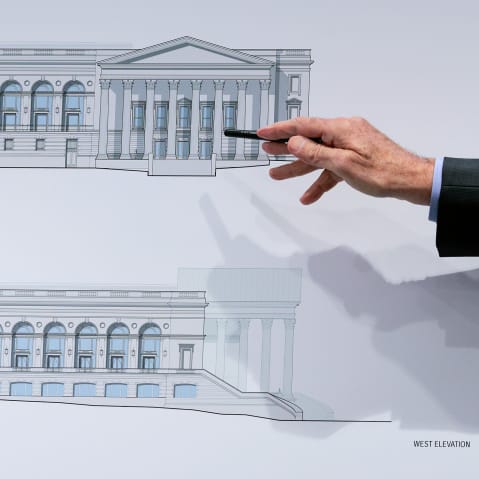 A hand holding a pen points to a drawing of the White House's ballroom.