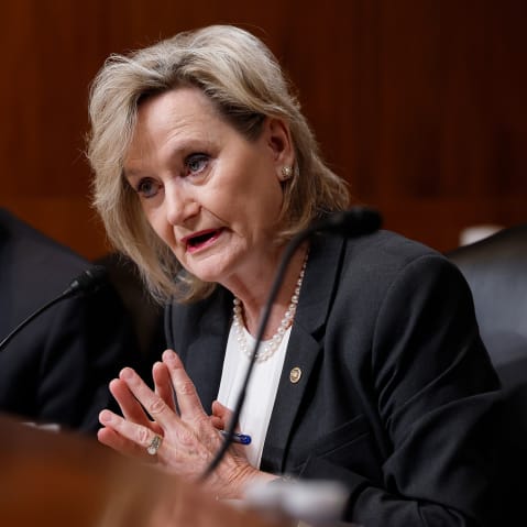 Cindy Hyde-Smith, right, speaks into a microphone.