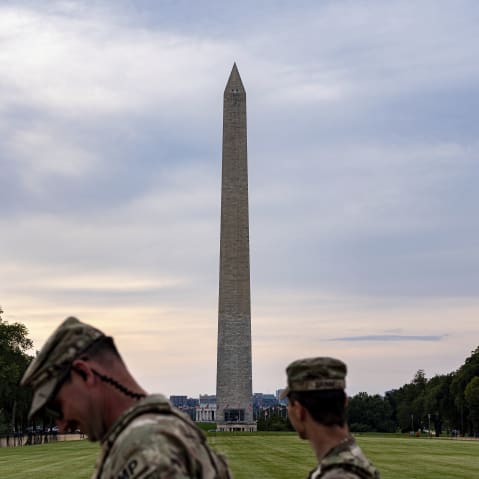 Two National Guardsmen walk in front of the Washington Monument