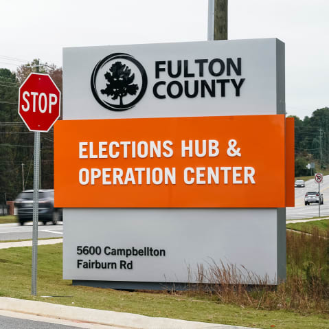 Vehicles pass by the sign for the Fulton County Elections Hub and Operations Center in Union City, GA.