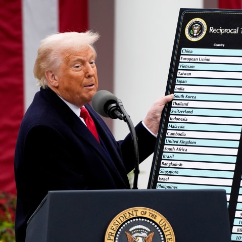 Donald Trump looks toward the audience as he holds a poster.