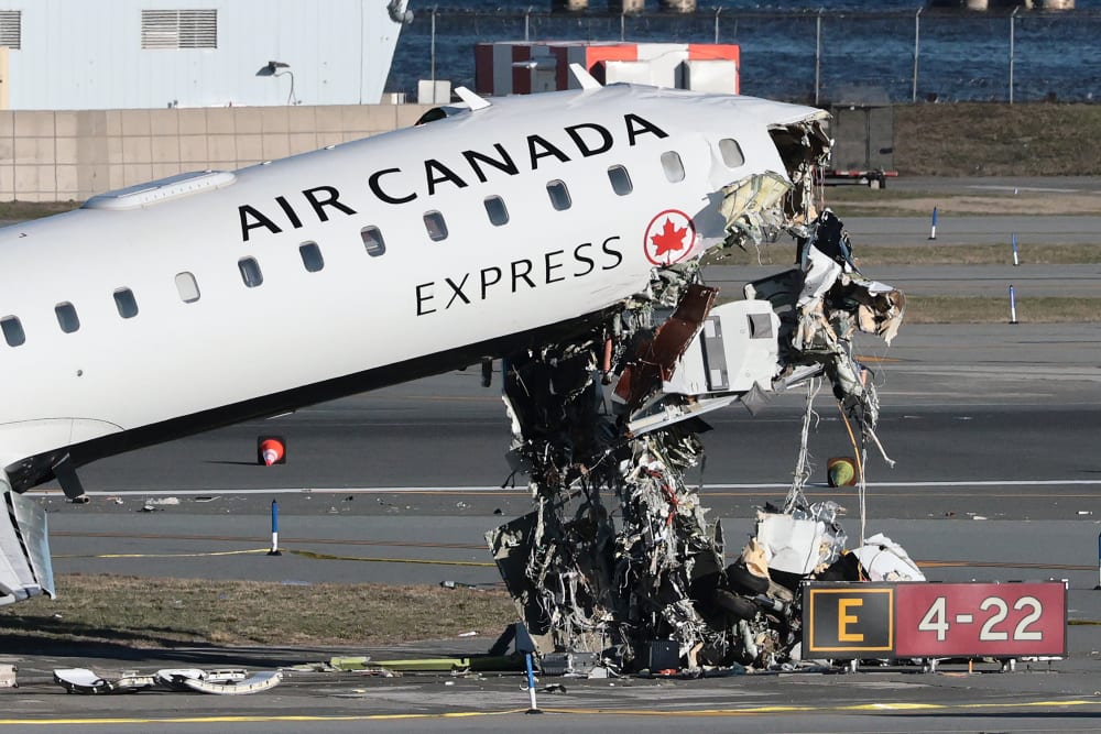 An Air Canada Express CRJ-900 sits on the runway after colliding with a Port Authority fire truck.