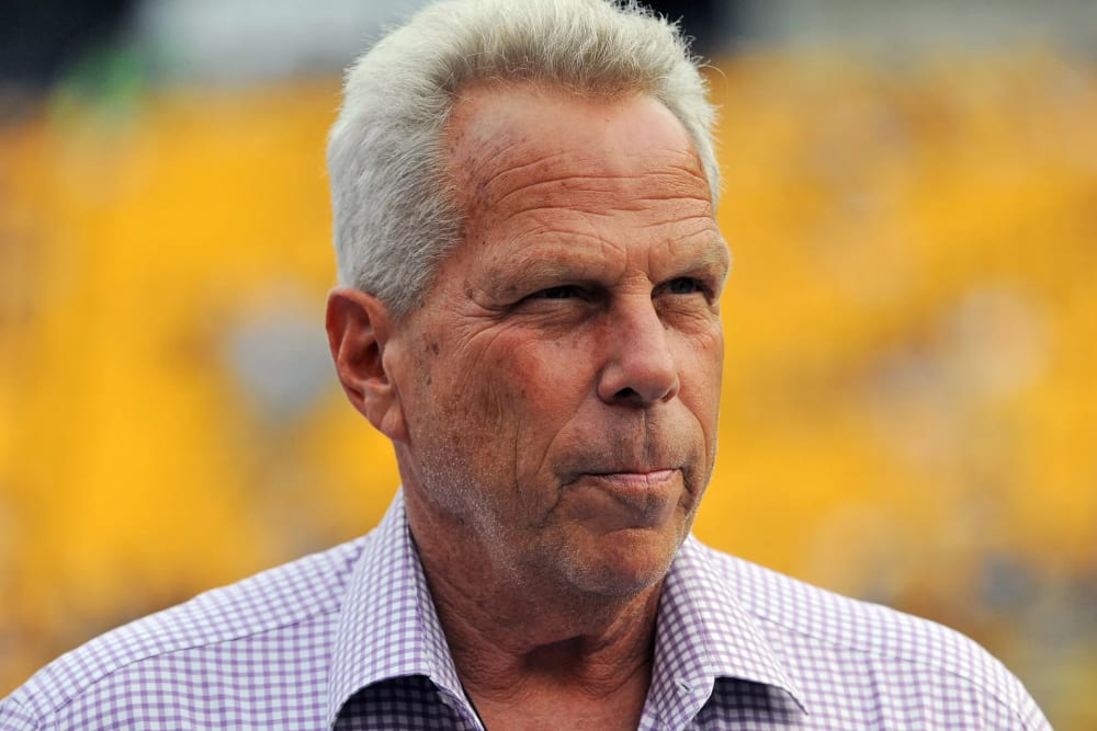 Steve Tisch is seen looking away in this closeup shot in front of a yellow background.