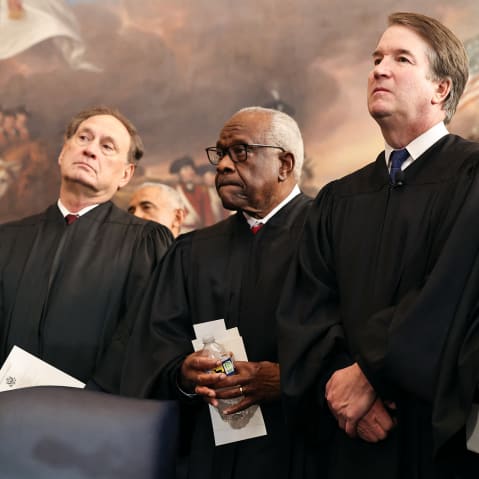 From left to right, Samuel Alito, Clarence Thomas, Brett Kavanaugh and John Roberts stand, dressed in robes.