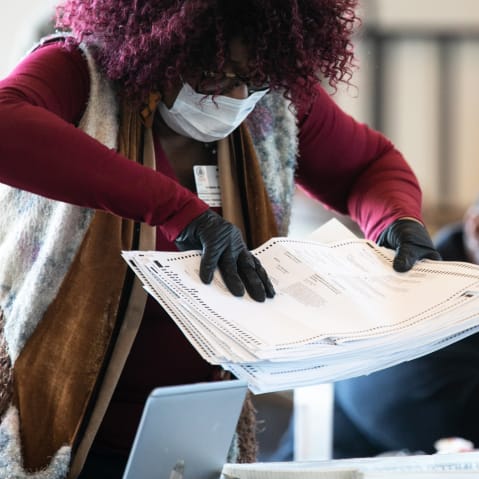 A Fulton county worker moves a stack of absentee ballots on Nov. 6, 2020 in Atlanta.