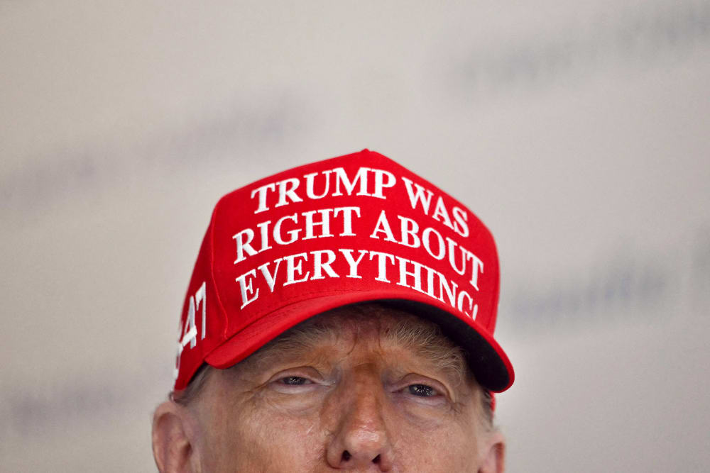 President Donald Trump wears a hat that reads "Trump was right about everything."