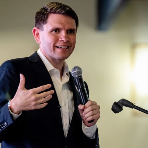 James Talarico speaks while holding a microphone.