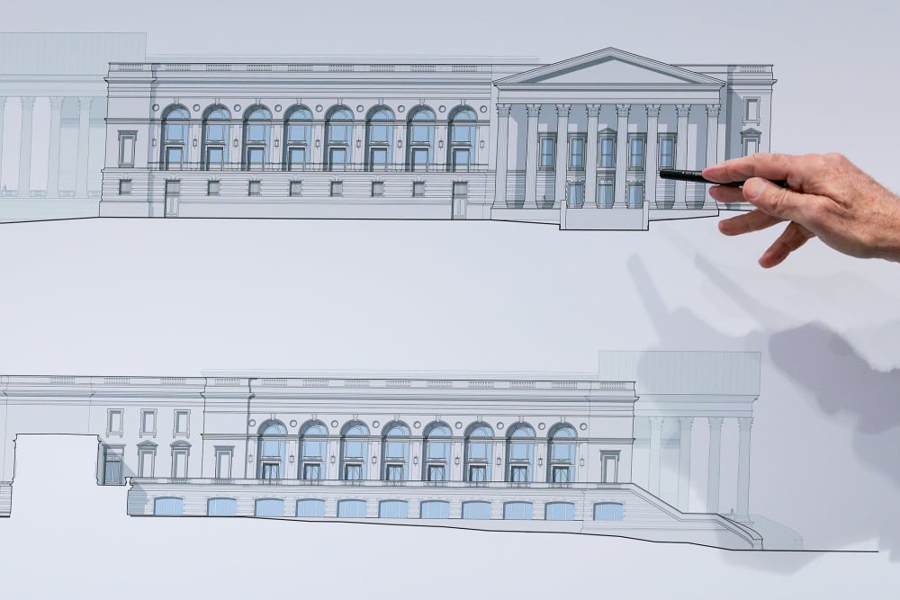 A hand holding a pen points to a drawing of the White House's ballroom.