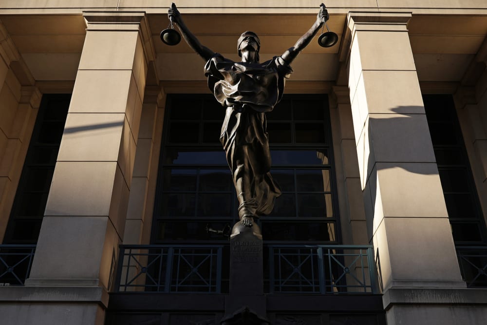 Light casts shadows over a statue of justice.