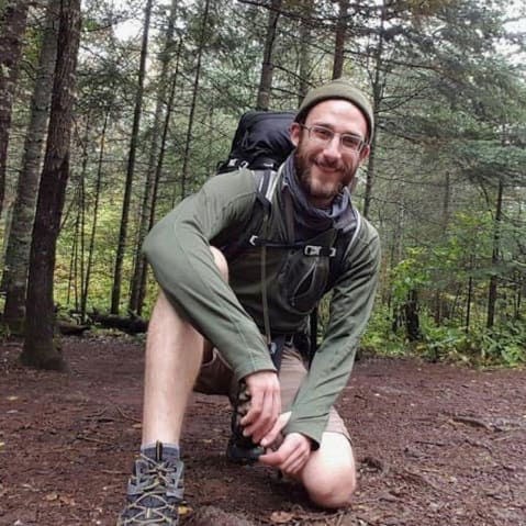 A selfie of a man backpacking in the woods