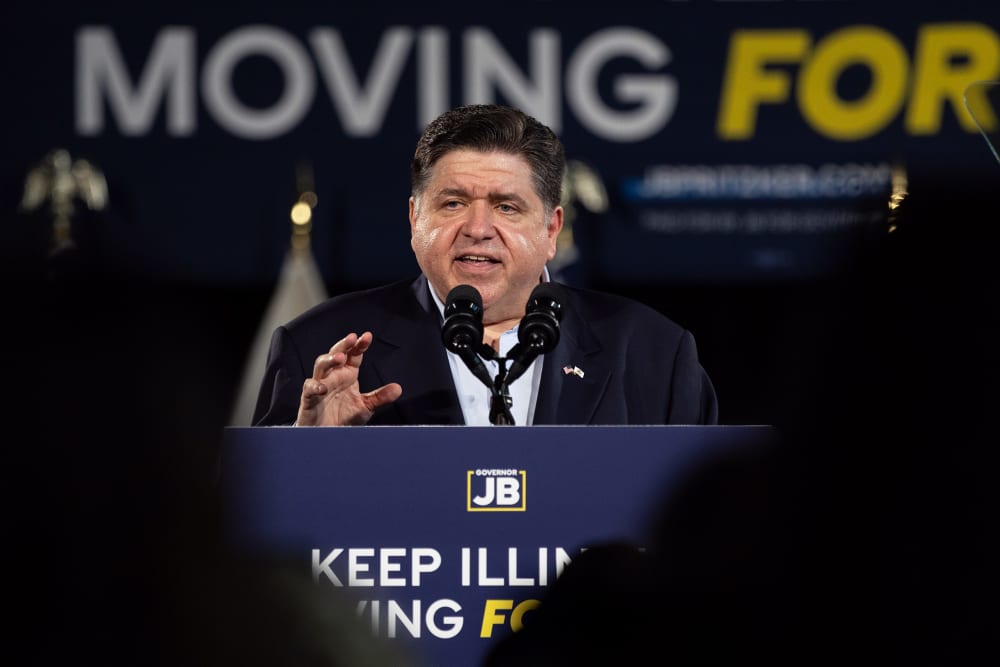 JB Pritzker speaks at a podium that says "Keep Illinois Moving Forward."