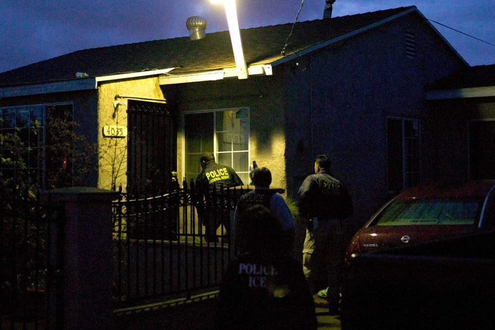 U.S. Immigration and Customs Enforcement agents in a predawn raid approach a house on March 7, 2006, in San Diego.