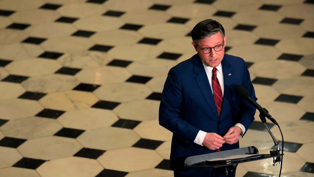 An aerial view of Speaker of the House Mike Johnson as he holds a news conference surrounded by the checkered floor of the Capitol.
