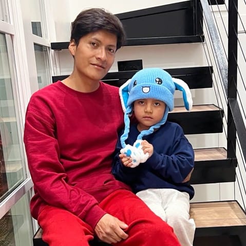 5 year old Liam Ramos, right, sits next to his dad on the steps of a staircase after being released from ICE detention.