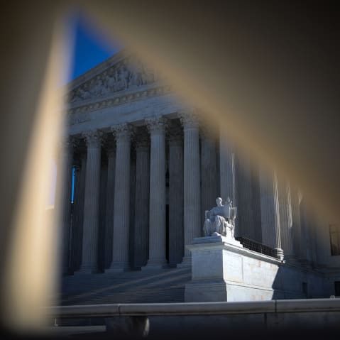 A sculpture in front of the supreme court building is seen through two pieces tarp.