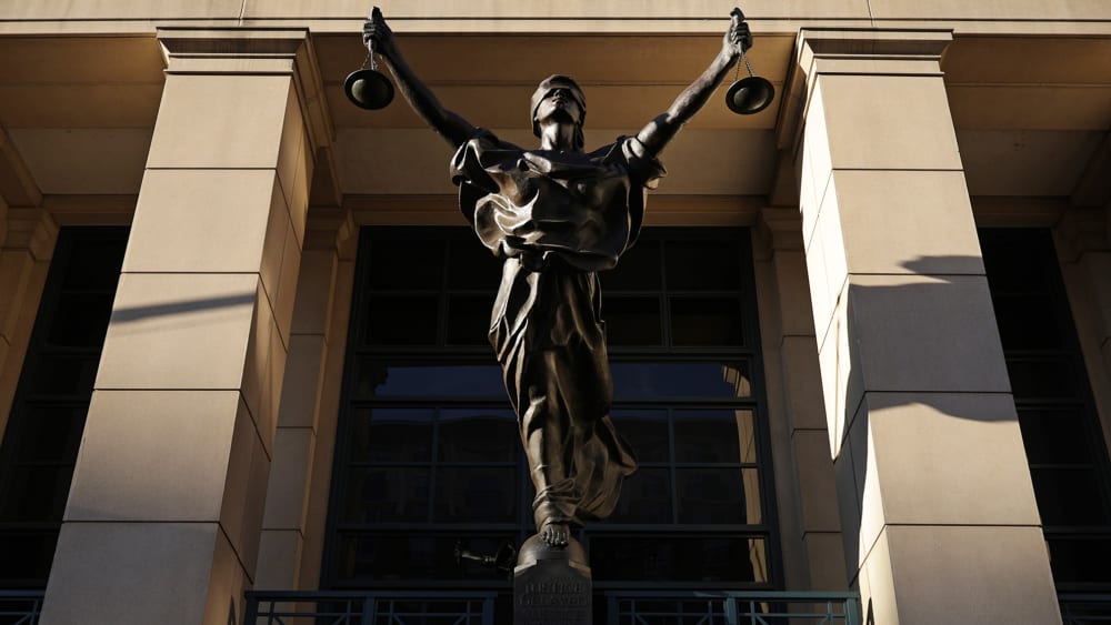 Light casts shadows over a statue of justice.
