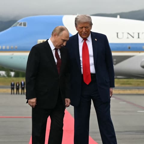 U.S. President Donald Trump, right, and Russian President Vladimir Putin pose on a podium on the tarmac after they arrived at Joint Base Elmendorf-Richardson in Anchorage.