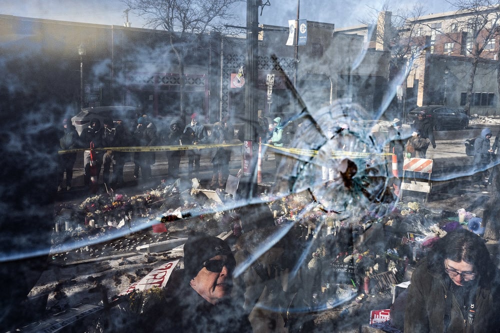 A gun shot perforation in a window pane in front of a makeshift memorial for Alex Pretti in Minneapolis.