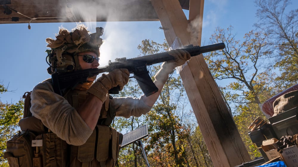 A person, backlit, shoots a gun.