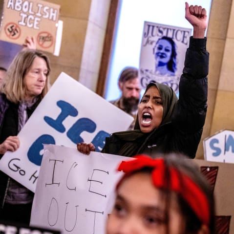 A female protestor shouts with her left fist raised during a protest.