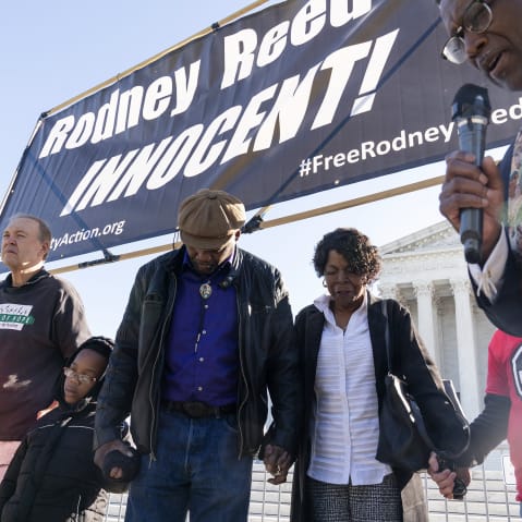 People hold hands looking down as they pray.