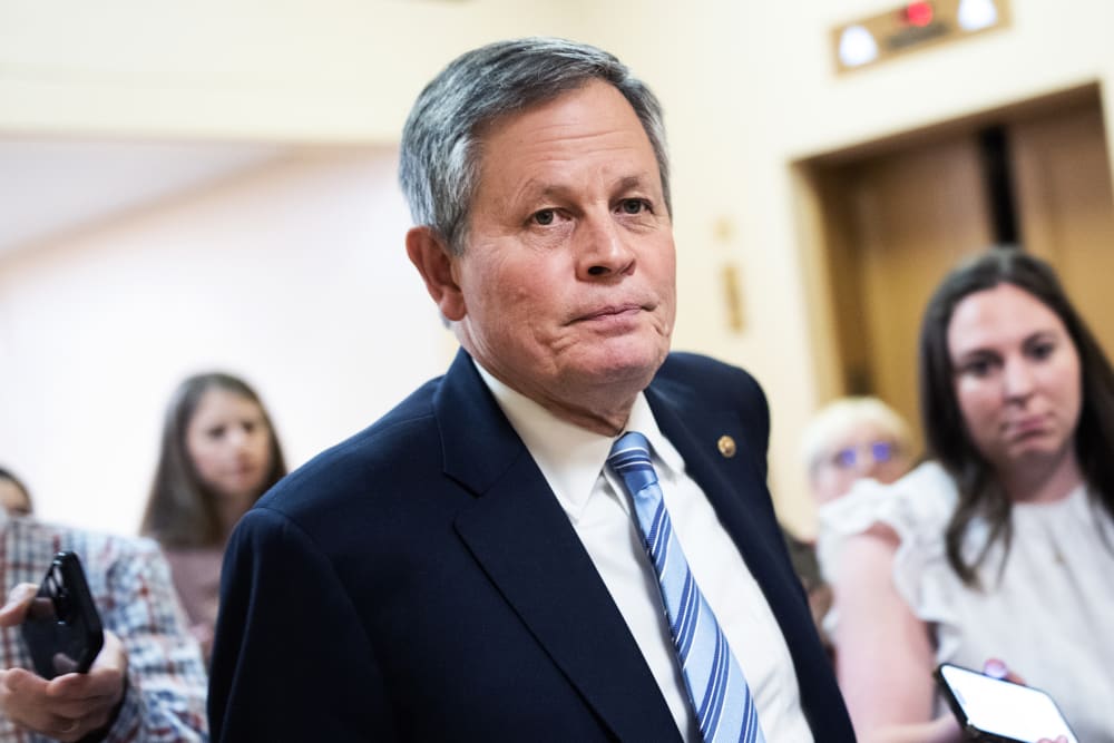 Steve Daniels walks in the direction of the camera as journalists follow him asking questions.