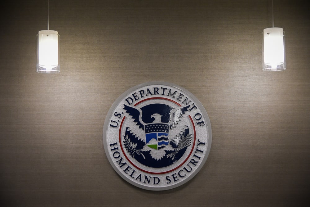 DHS logo is seen on a wall along with two light fixtures on both sides of it.