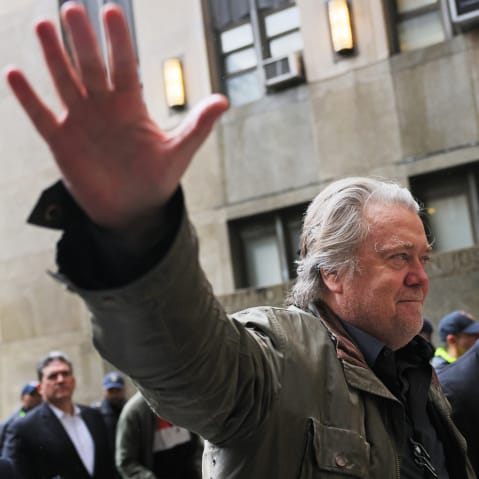 Steve Bannon waves his hand while walking into the court building.