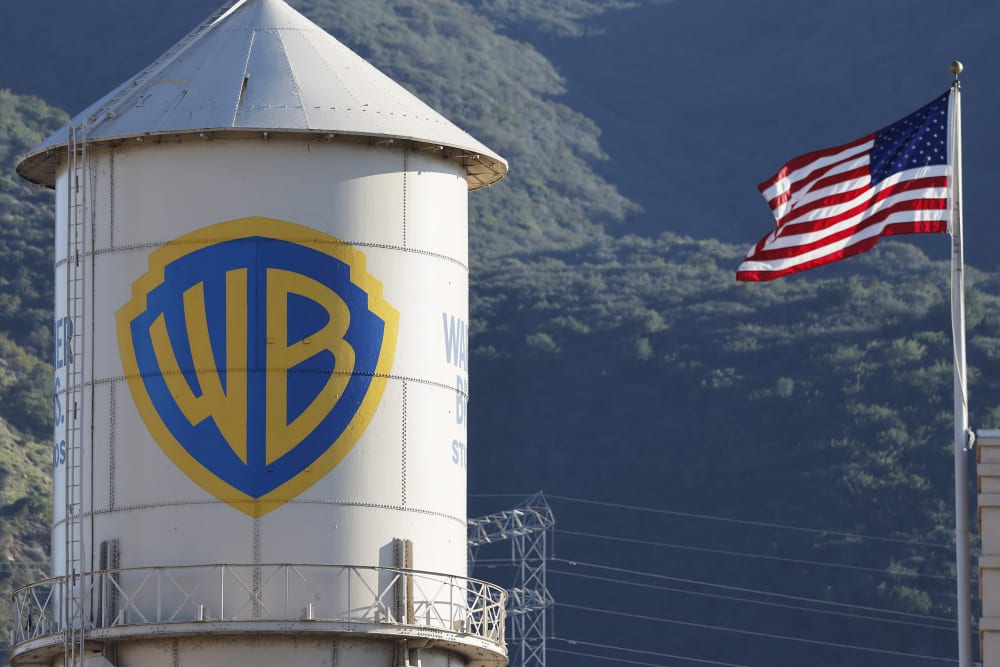 Warner Bros. logo is seen on the left, and the American flag is on the right.