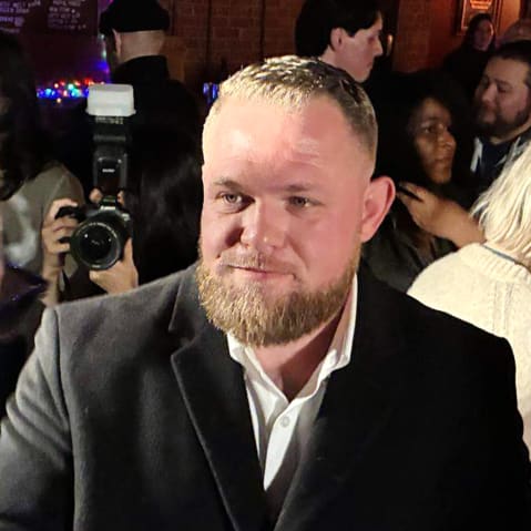 Taylor Rehmet is talking to a man at a party.