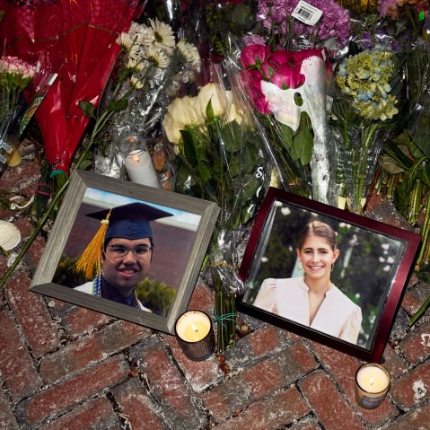 Lit candles and flowers rest by framed photos of mass shooting victims MukhammadAziz Amurzokov and Ella Cook at a memorial near Brown University.