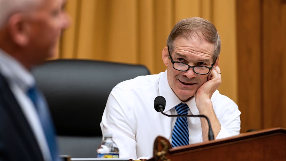 Jim Jordan, right, rests his head on his hand as he talks to a person turned away from the camera.