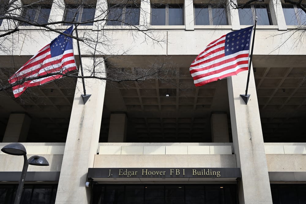 FBI headquarters sign is seen between two American flags.